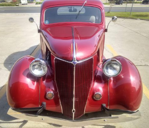 Front view of a shiny red vintage car parked on pavement