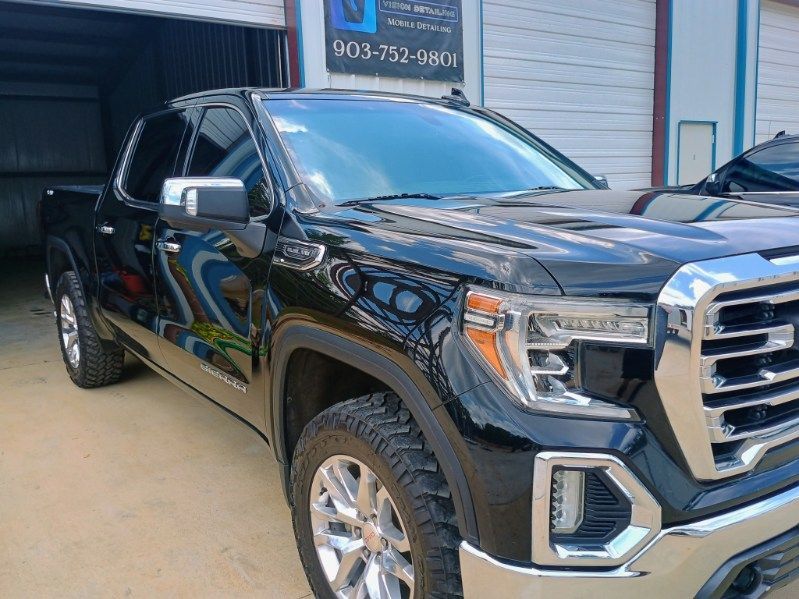 Black pickup truck parked outside a garage with chrome grille and wheels