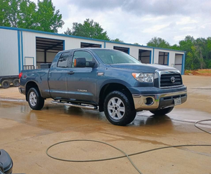 Gray pickup truck parked on a wet lot in front of portable office buildings
