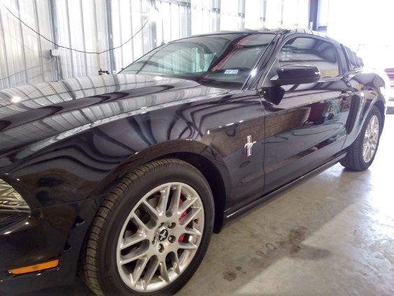 Black sports coupe with silver wheels parked indoors in a garage