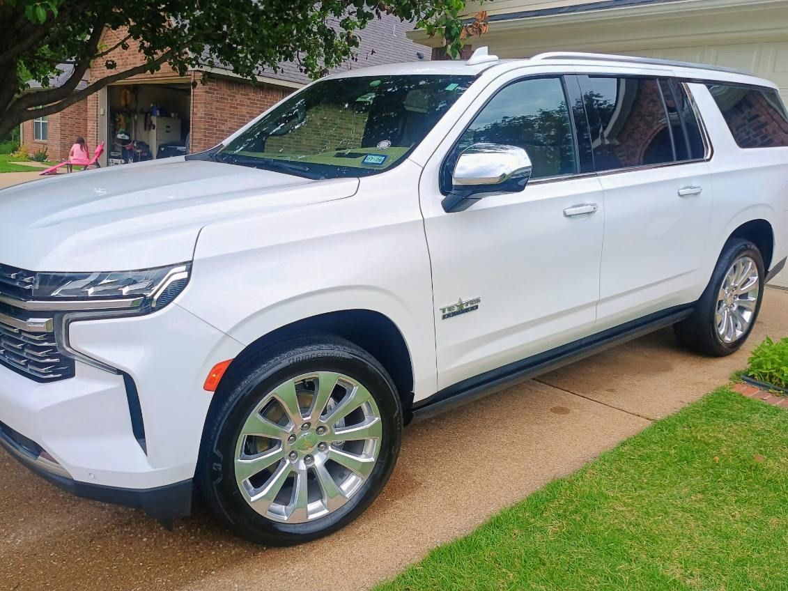 White SUV parked in a driveway beside a lawn and house