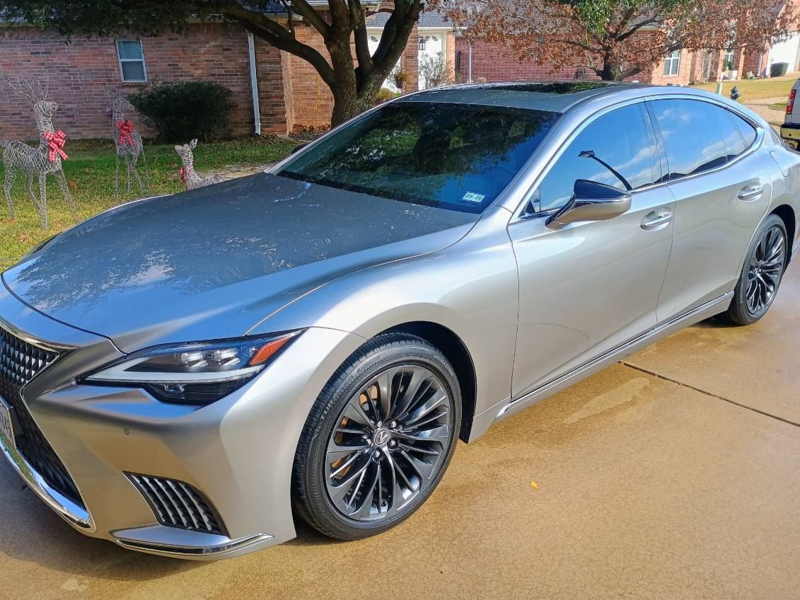 Silver sedan parked on a wet driveway in front of a brick house