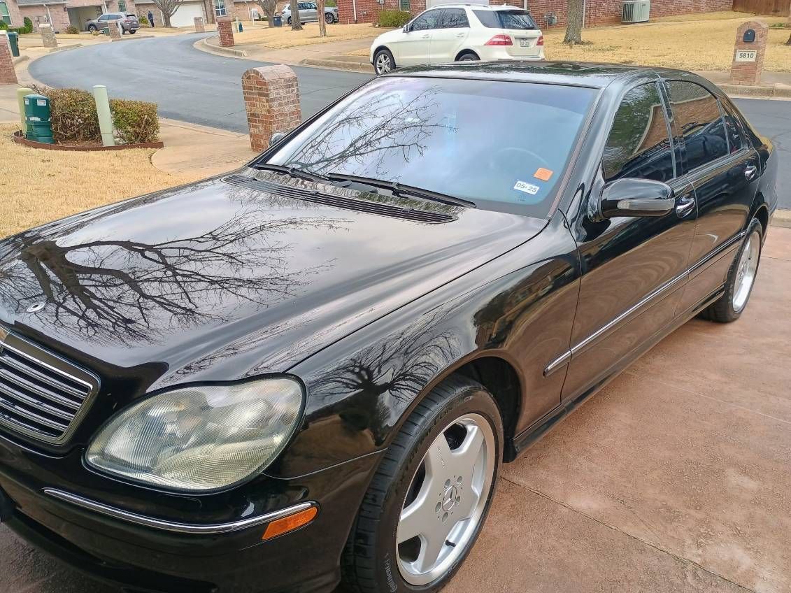 Black sedan parked on a wet driveway beside a suburban street