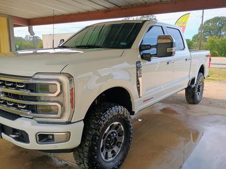 White lifted pickup truck parked under a covered area with wet pavement