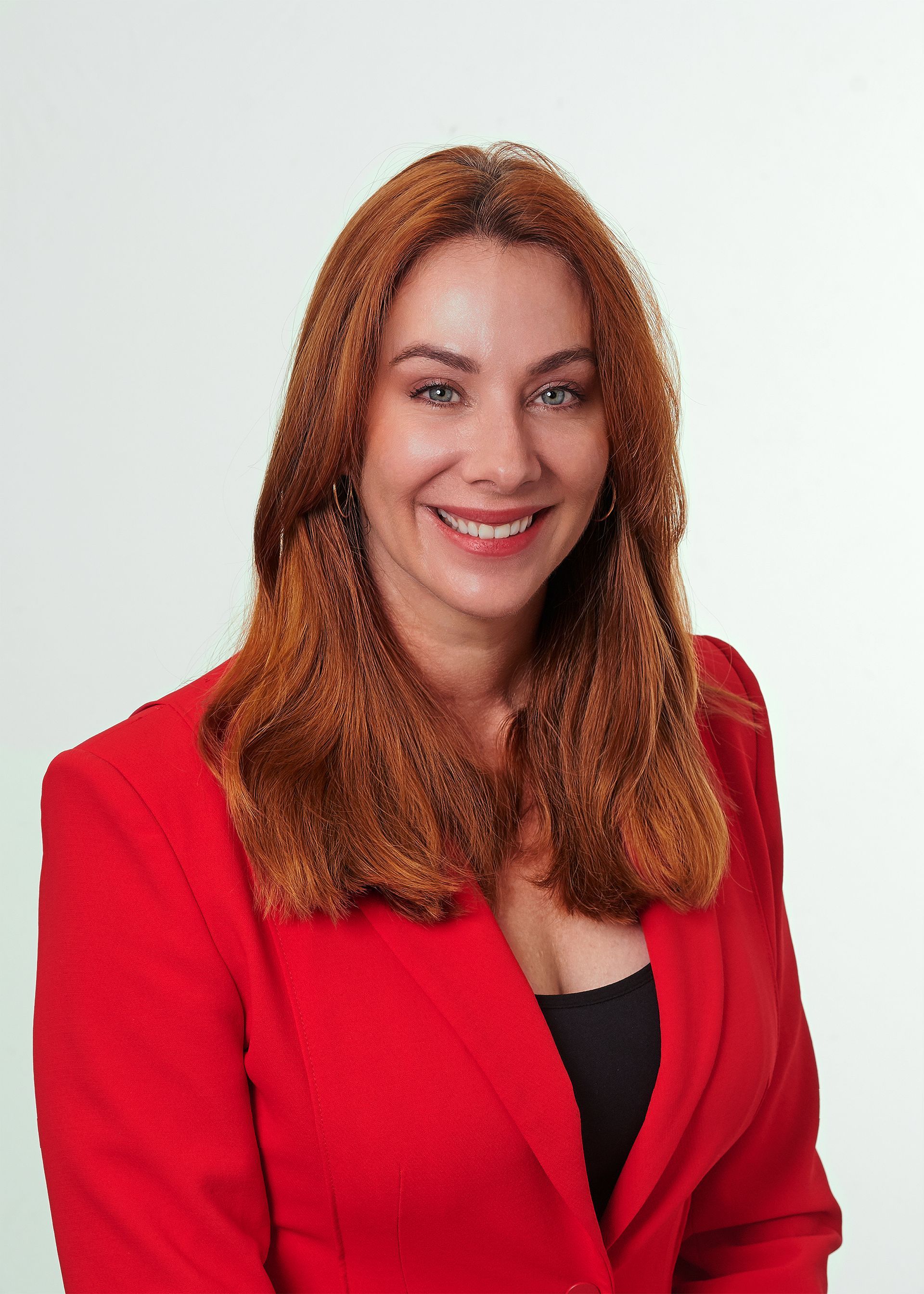A woman in a red jacket is smiling for the camera.