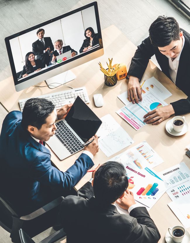 A group of business people are sitting around a table having a meeting.