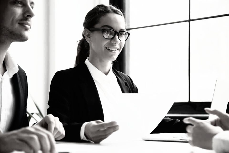 A woman is sitting at a table holding a piece of paper.