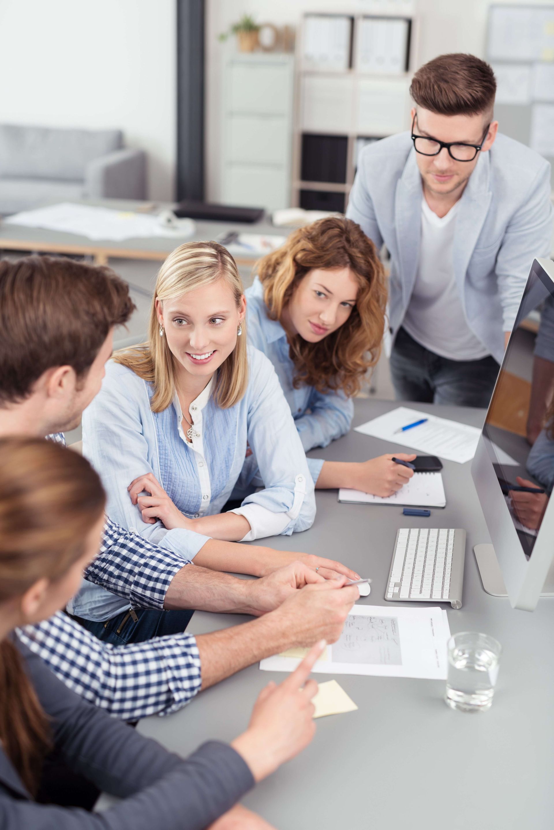 A group of people are sitting around a table looking at a computer screen.