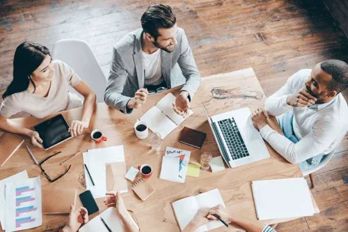 A group of people are sitting around a table having a meeting.