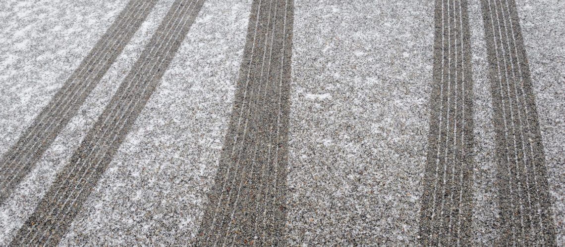 Tire tracks in snow on a gray surface.