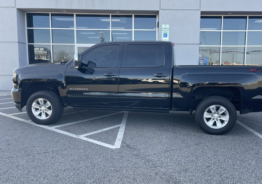 A black pickup truck parked in a parking lot at Bells Fork Truck and Auto Service