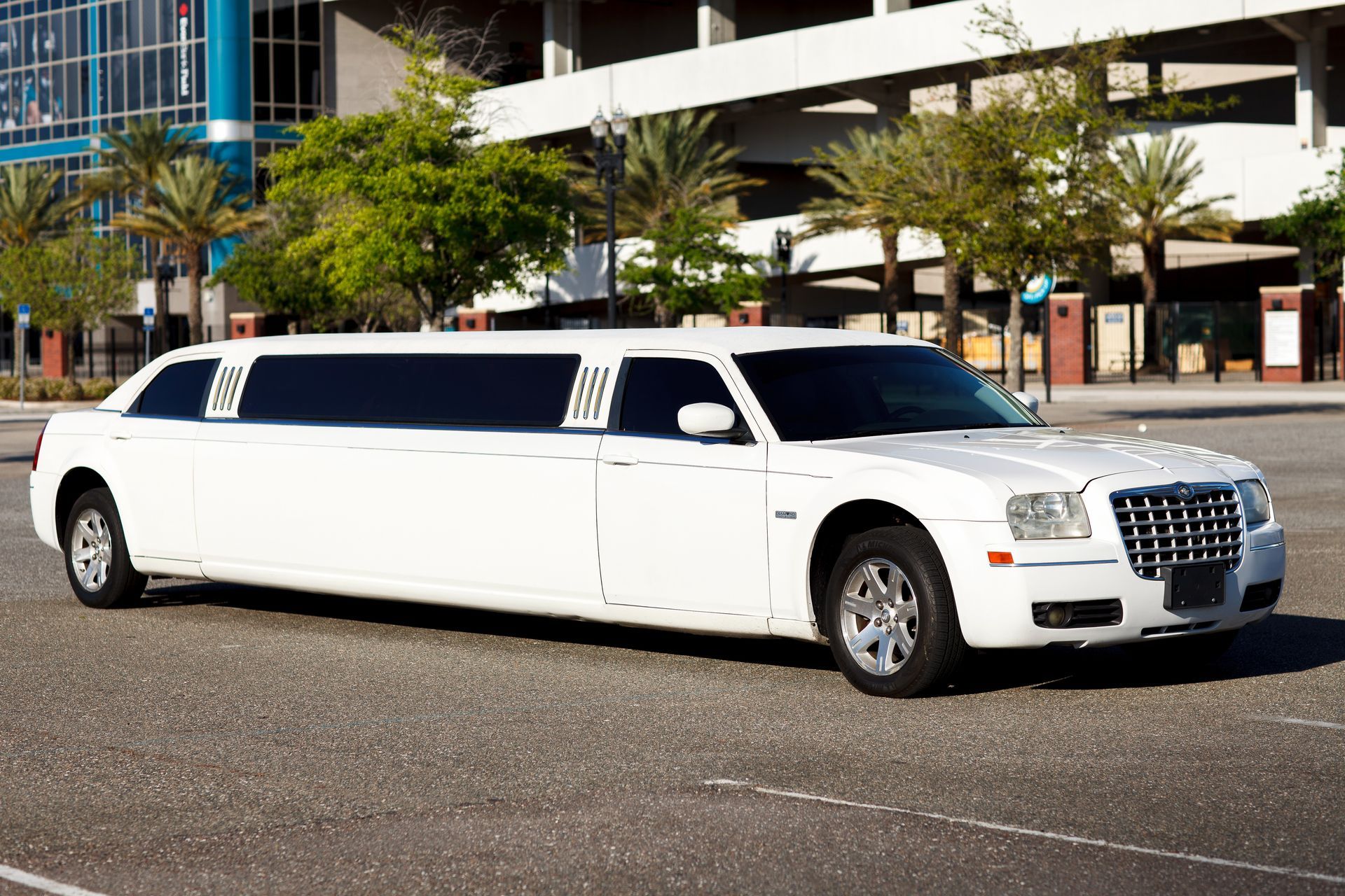 White stretch limousine parked on a city street in front of a building.