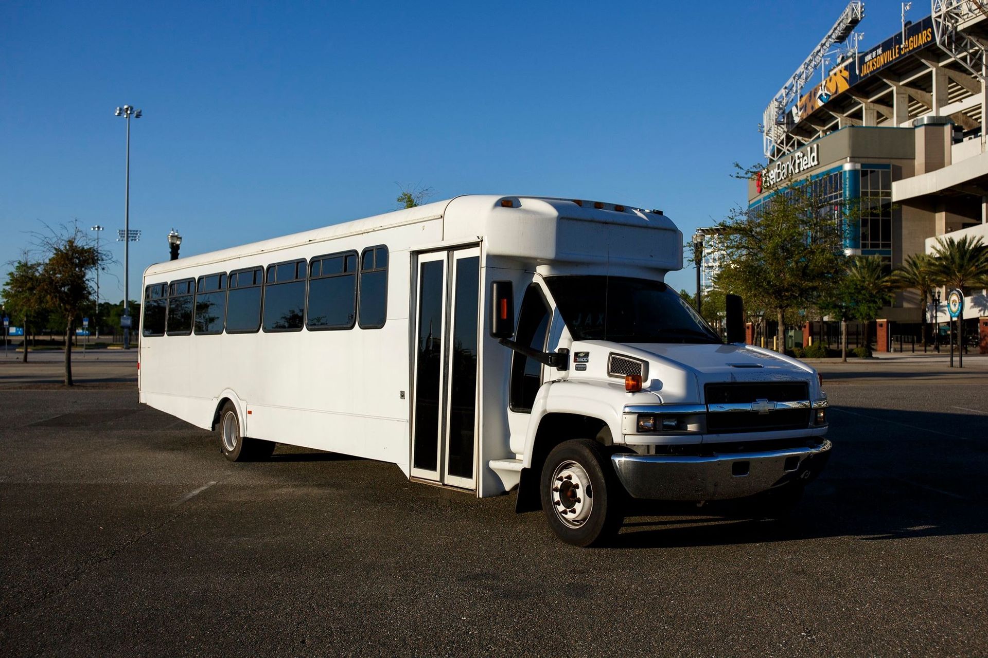 White shuttle bus parked in a lot on a sunny day