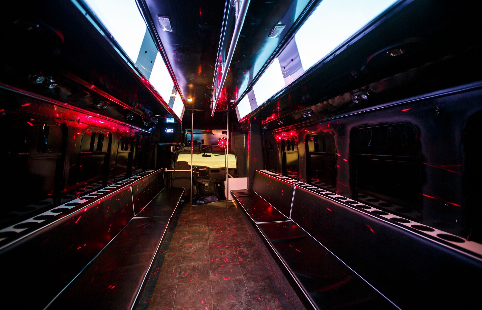 Empty bus interior with neon red and blue lighting, centered aisle, and rows of seats on both sides