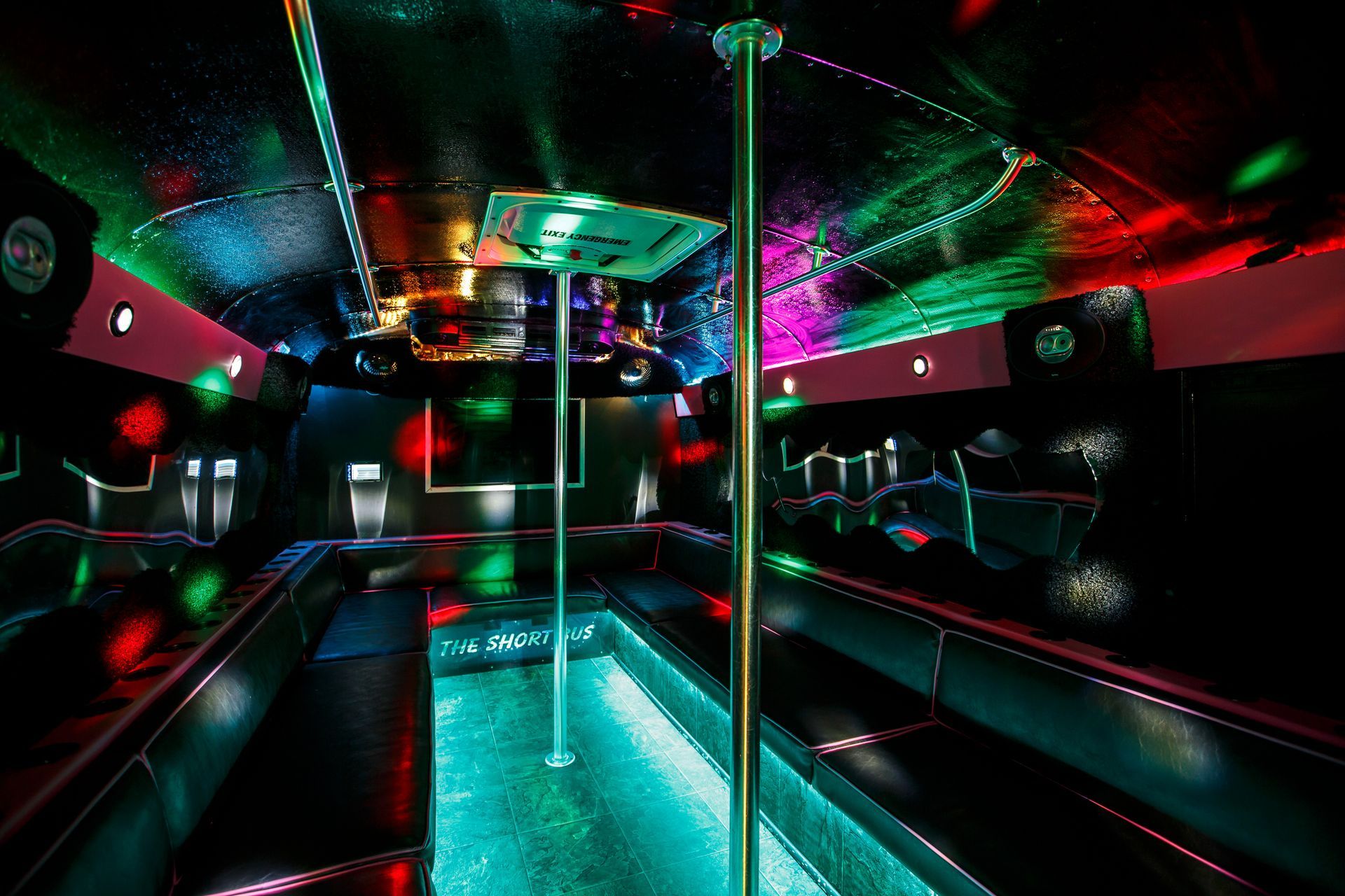 Neon-lit nightclub interior with a turquoise dance floor, mirrored walls, and colorful ceiling lights
