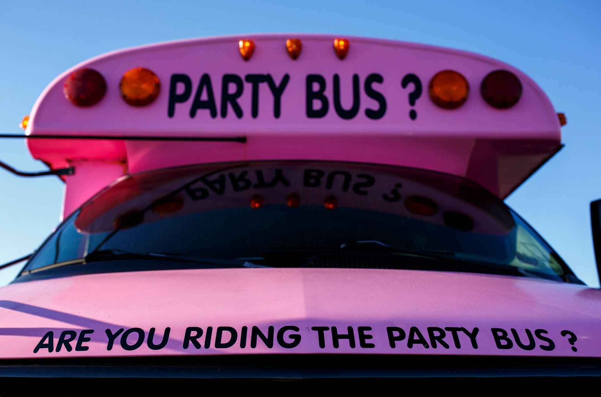 Pink party bus sign on a vehicle roof with the words “PARTY BUS?” and “ARE YOU RIDING THE PARTY BUS?”