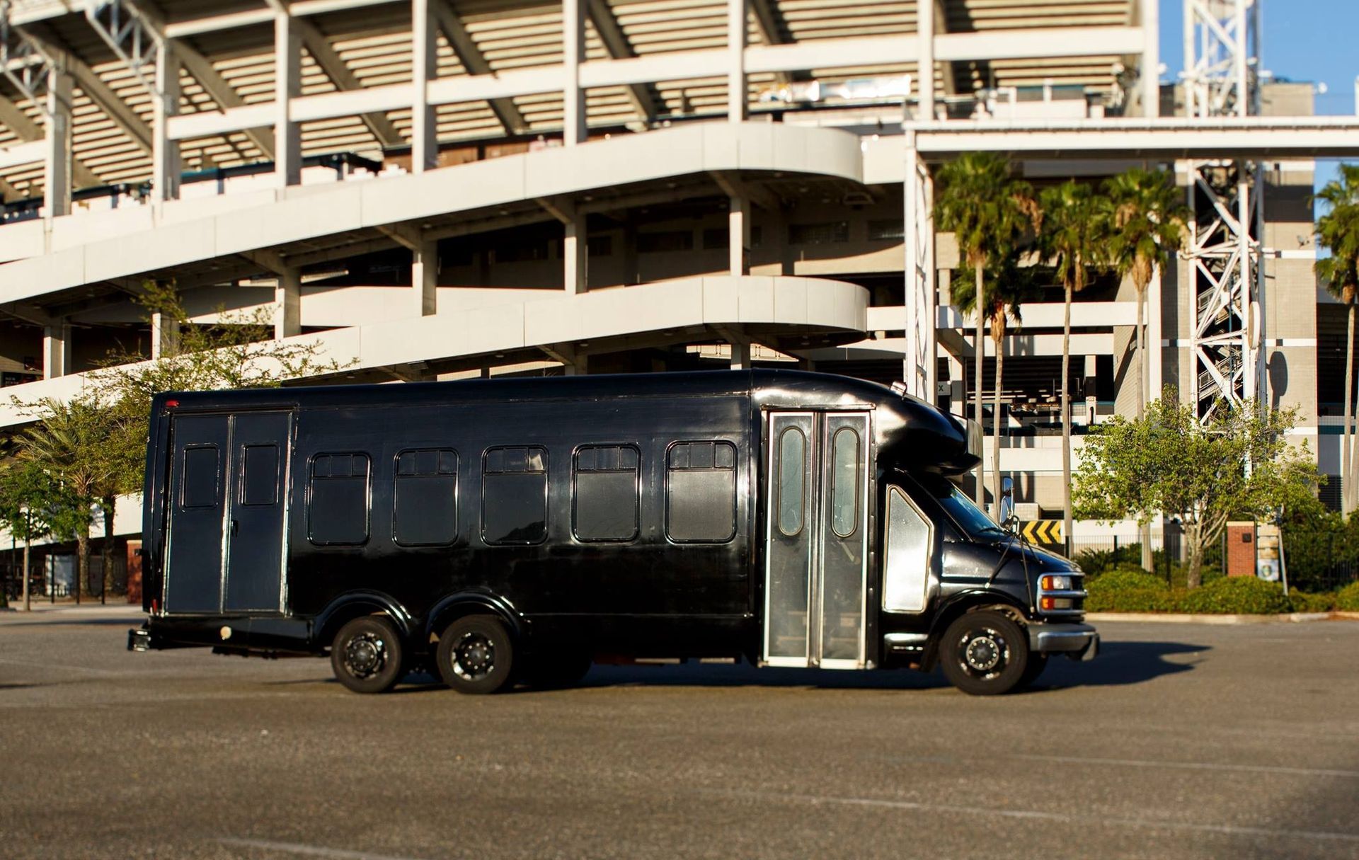Black coach bus parked in front of a stadium entrance.