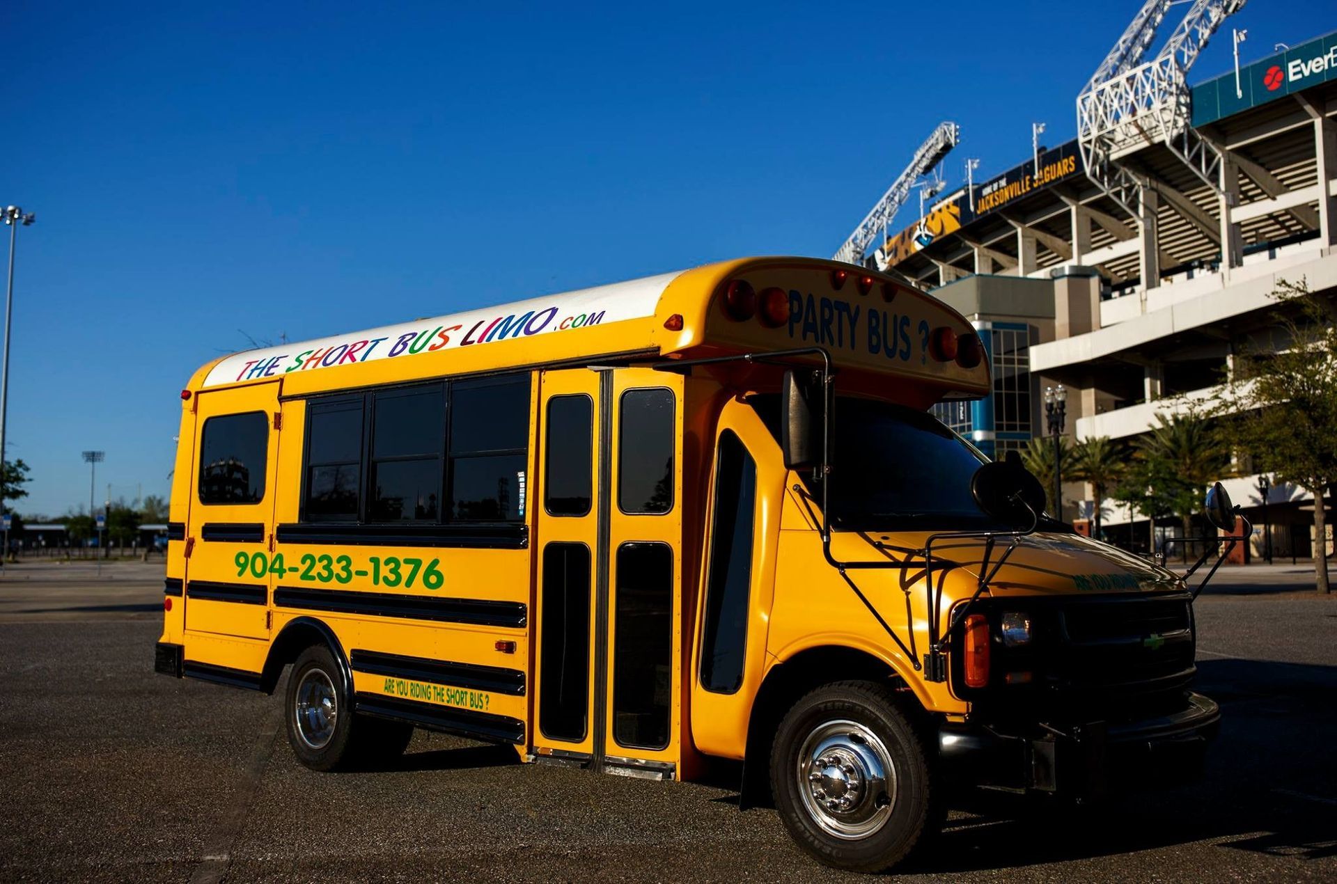 Yellow school bus parked outside a stadium on a sunny day
