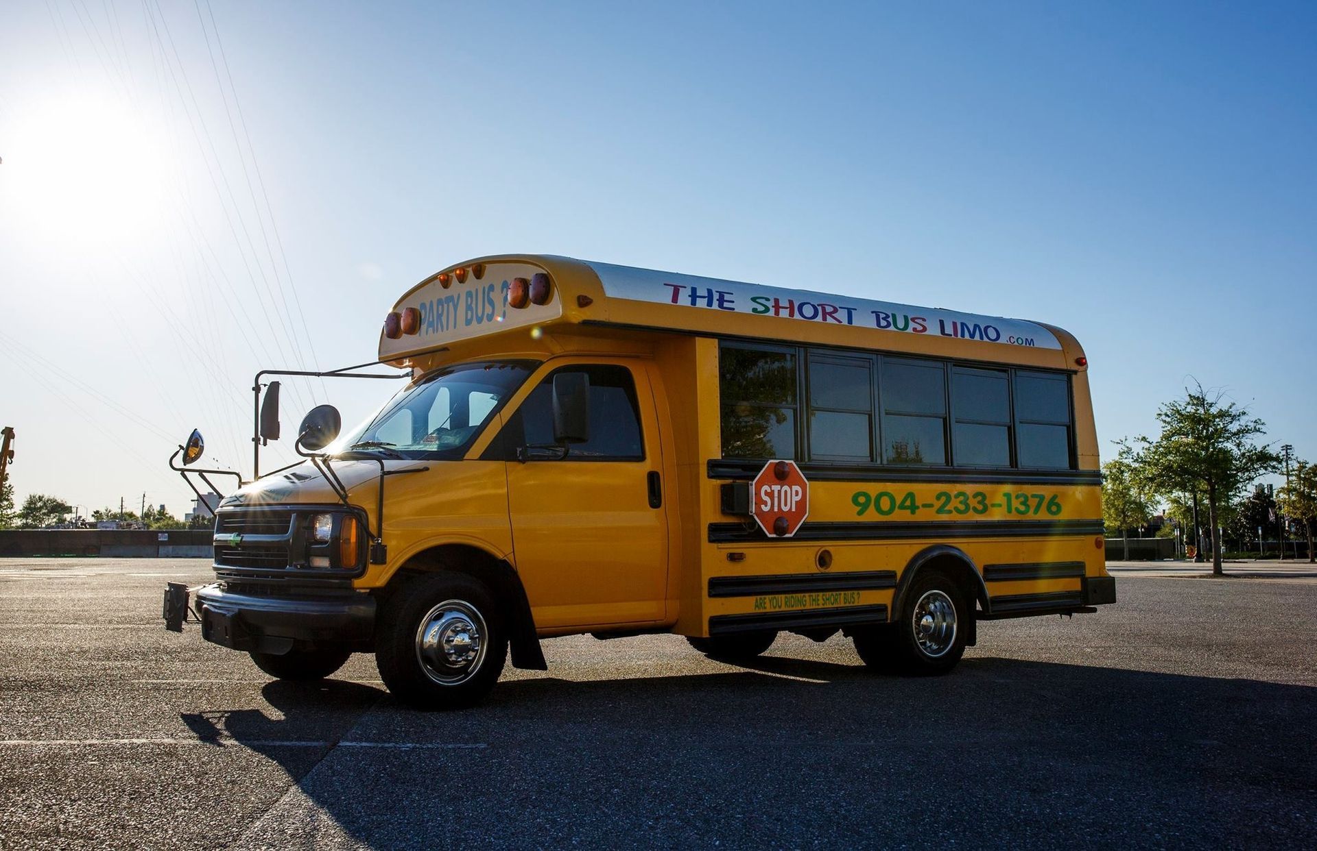 Yellow school bus parked on a gravel lot under a bright blue sky