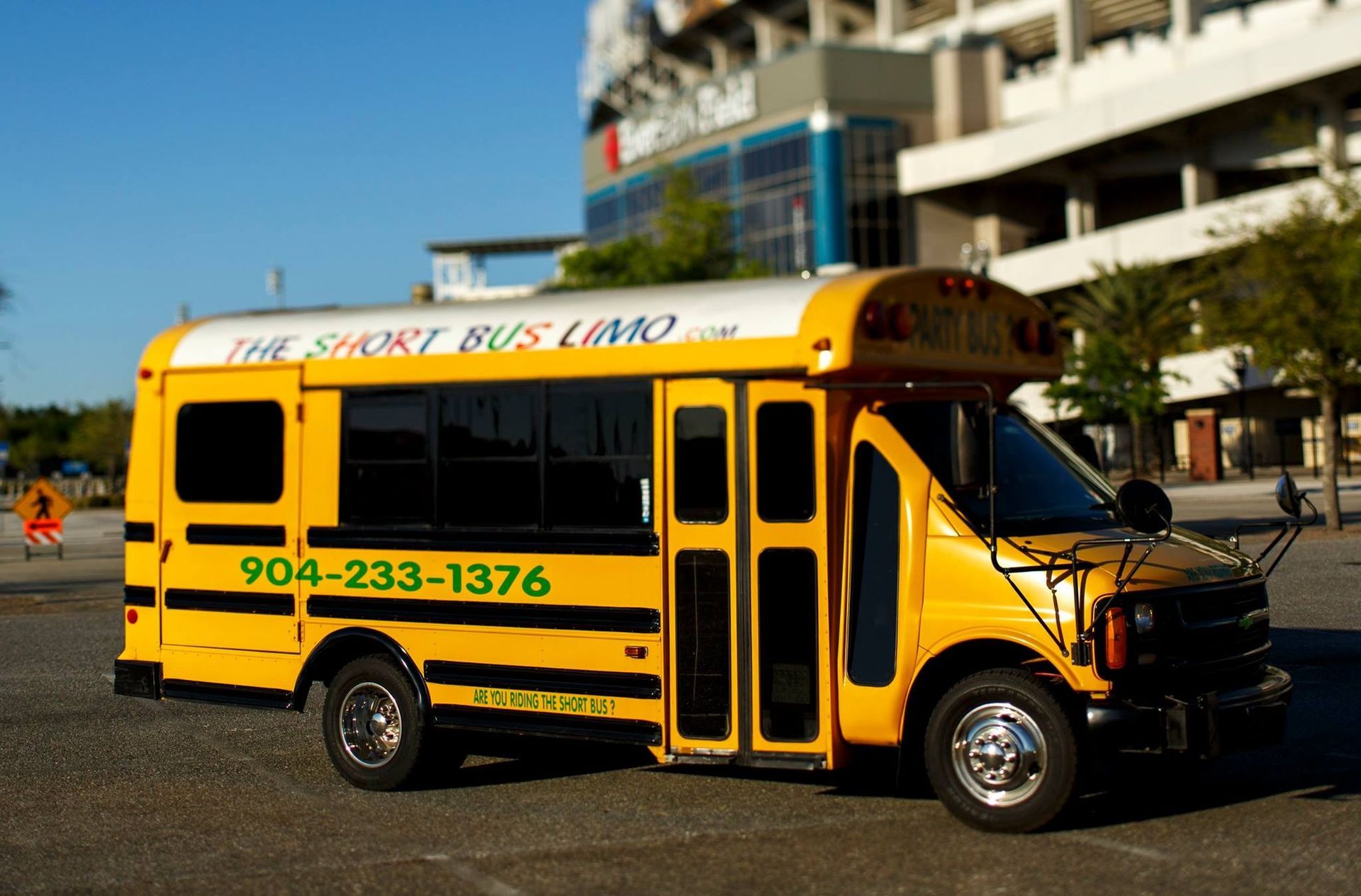 Yellow shuttle bus parked outdoors in front of a modern building