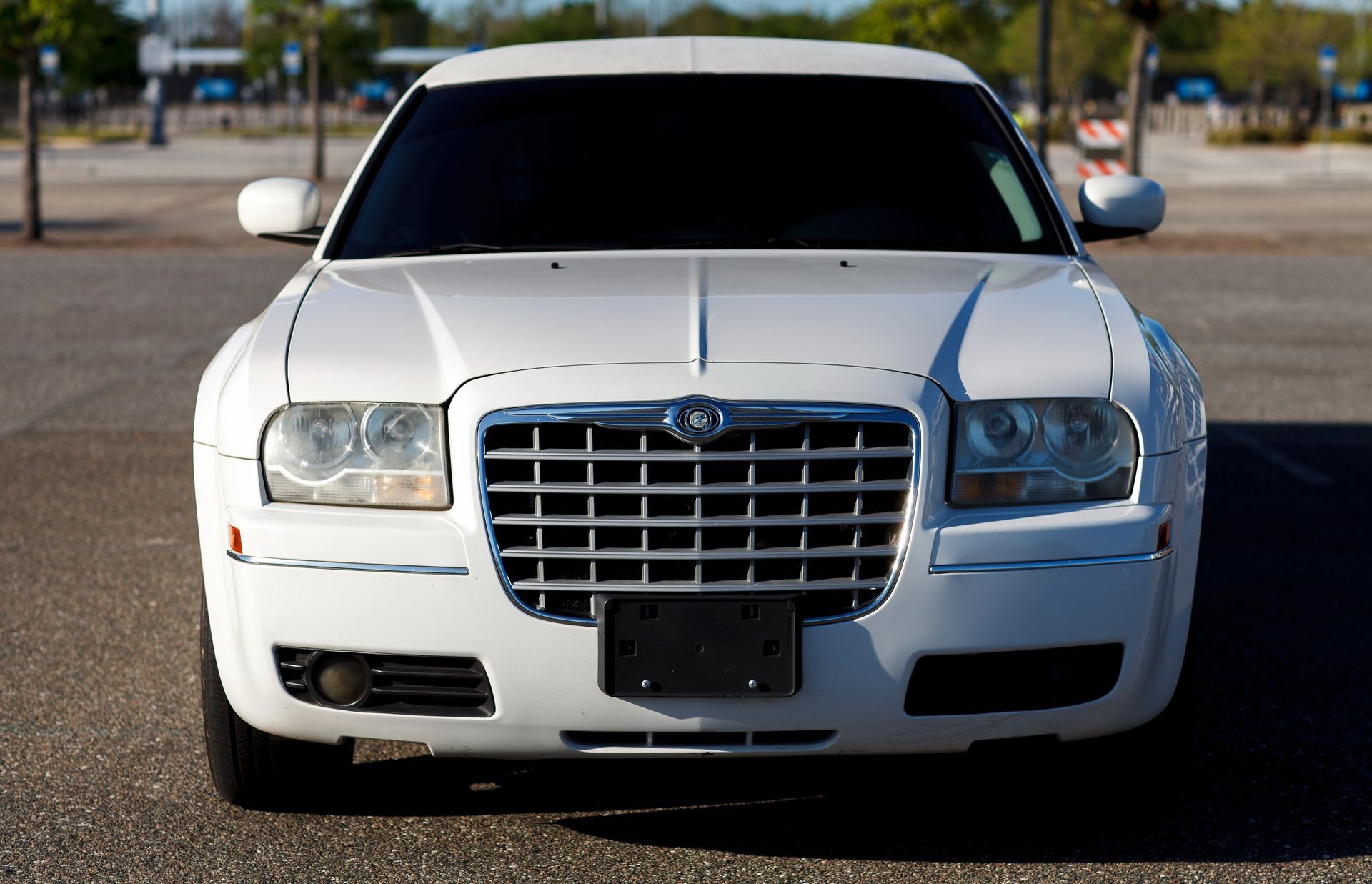 Front view of a white sedan parked on pavement in bright daylight