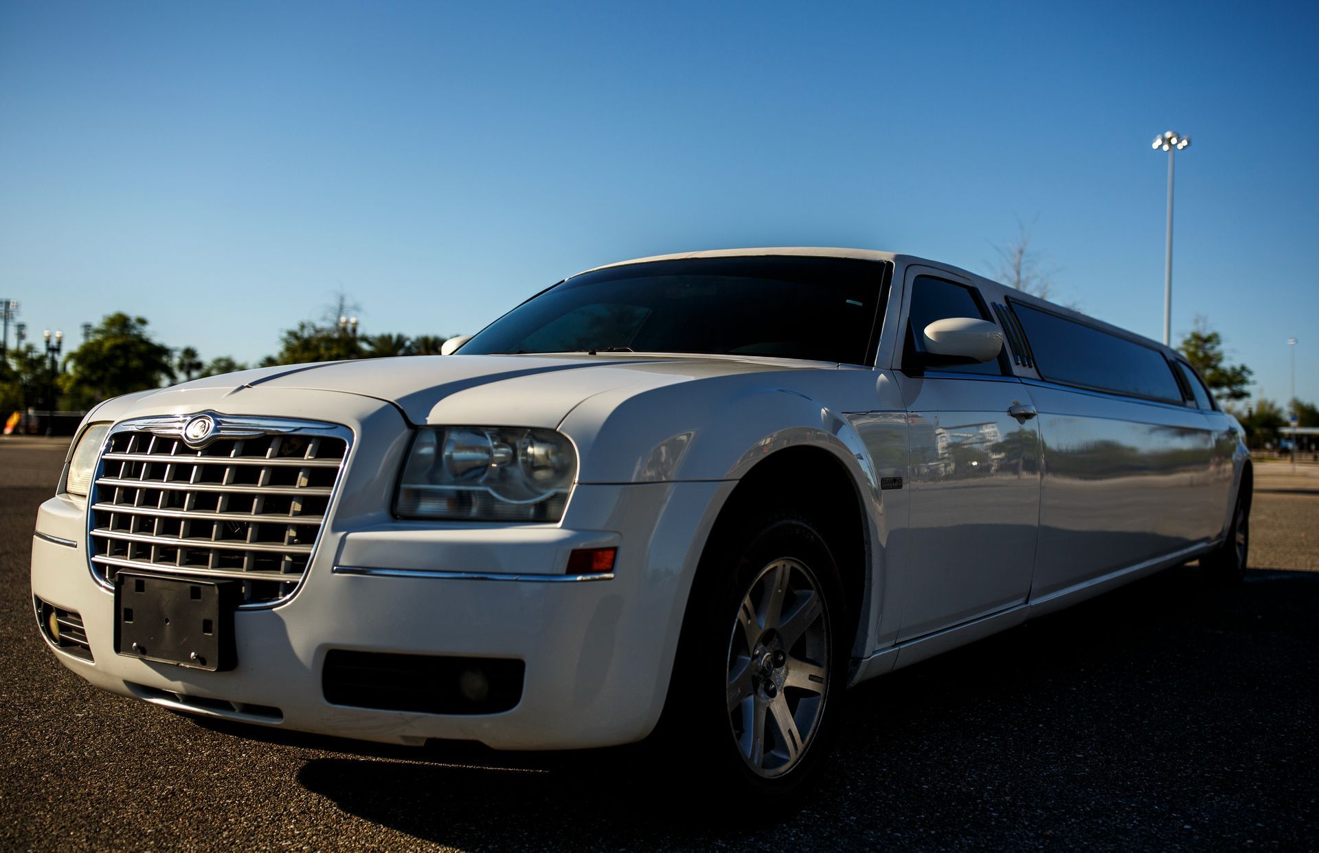 White stretch limousine parked outdoors under a clear blue sky