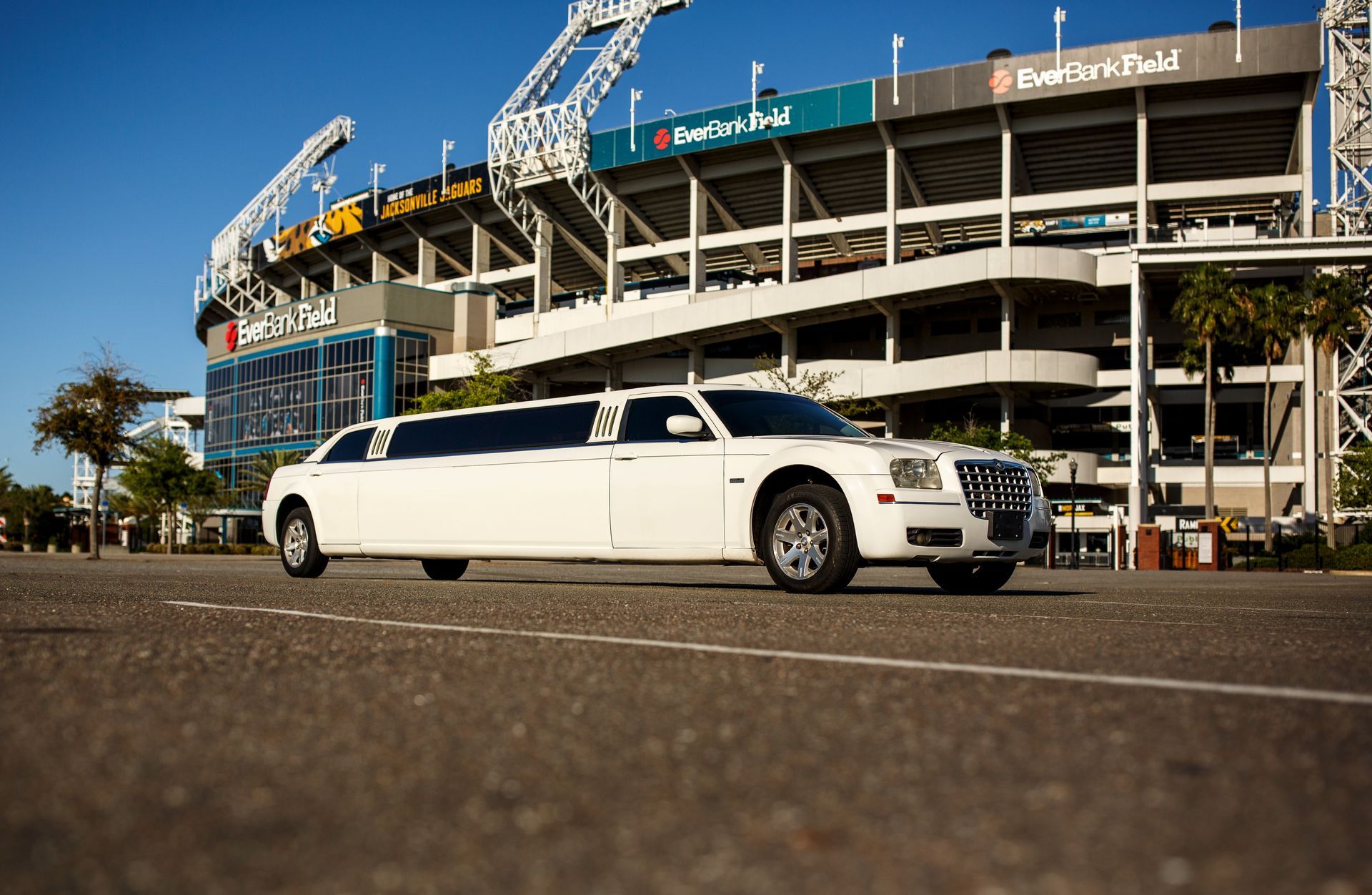 White stretch limousine parked outside a stadium with a blue façade and signage