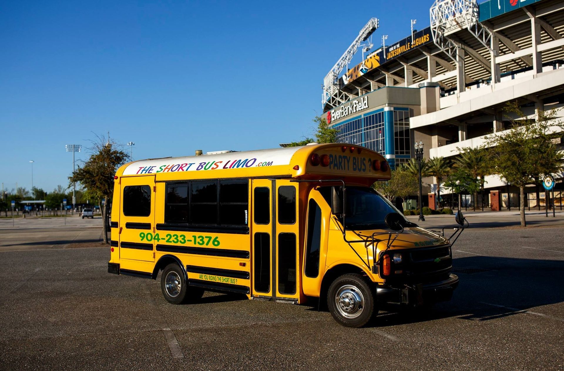 Yellow school bus parked near a stadium in a sunny lot