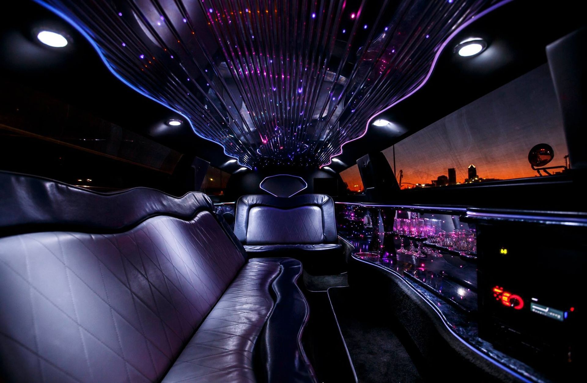 Luxury limousine interior with purple ceiling lights and leather seating at dusk