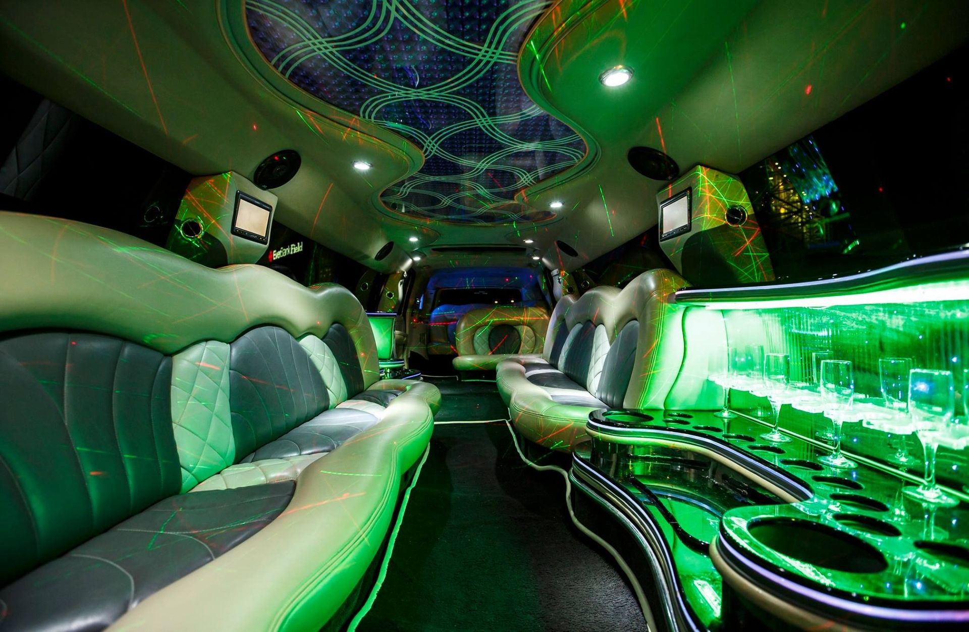 Green-lit luxury limousine interior with white leather seating and glossy black trim