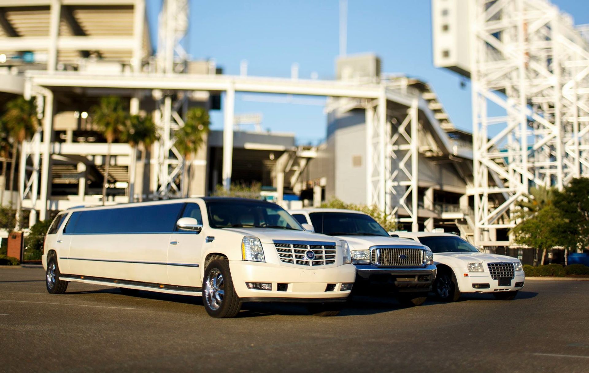 Three luxury limousines parked outside a modern building in daylight