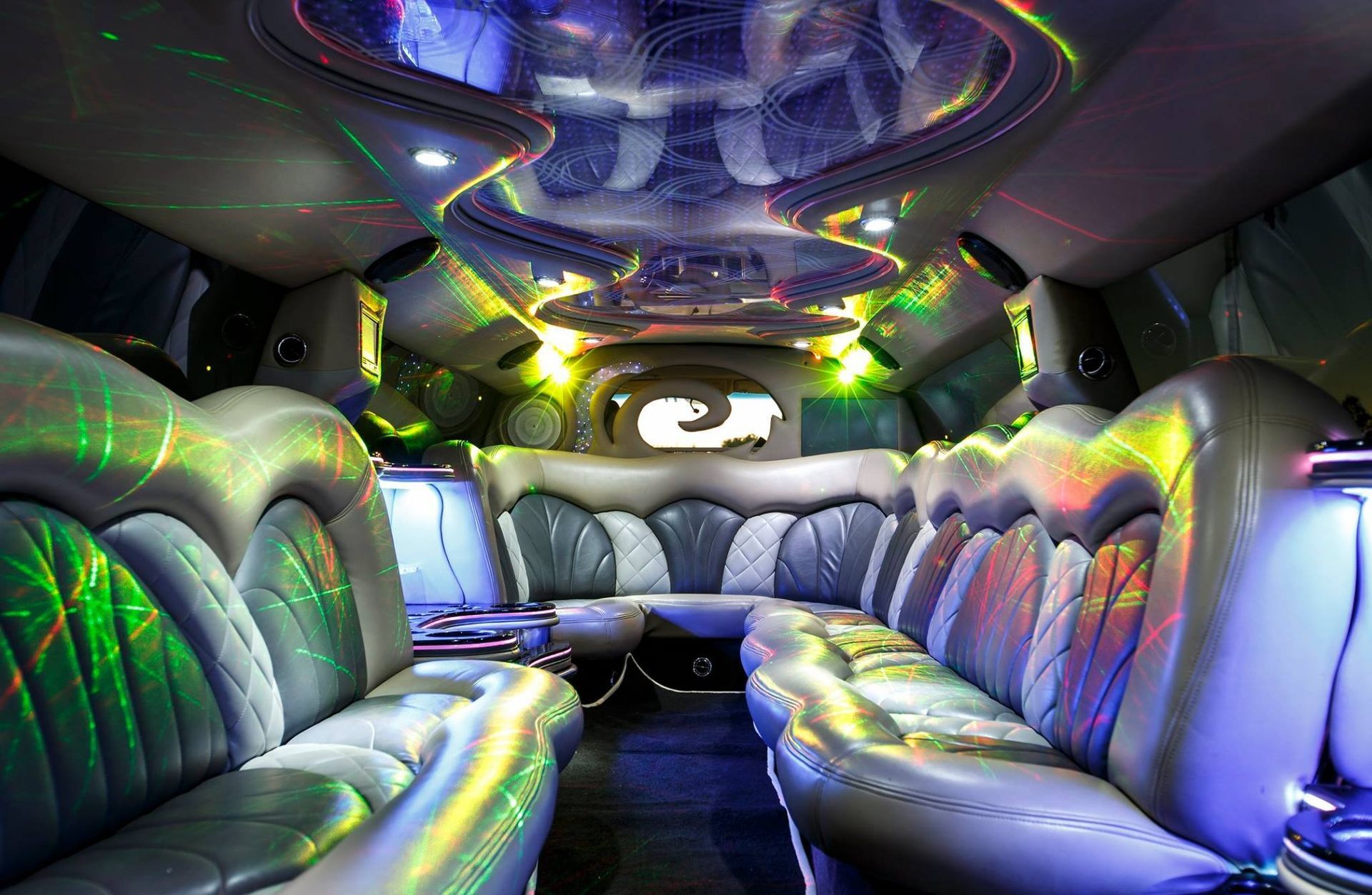 Futuristic limo interior with silver leather seats and colorful LED lighting throughout the cabin