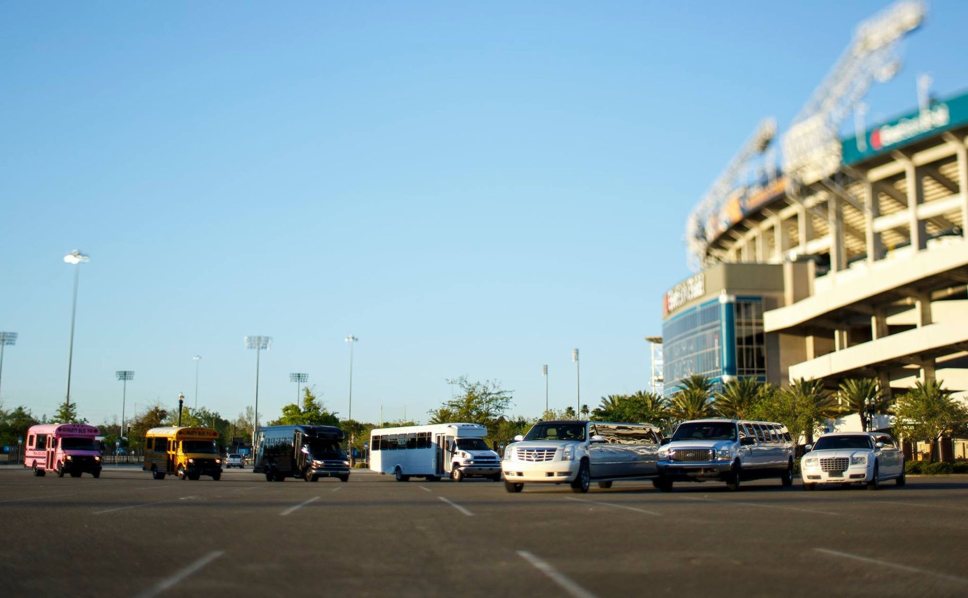 Parking lot with several cars beside a large stadium under a clear blue sky