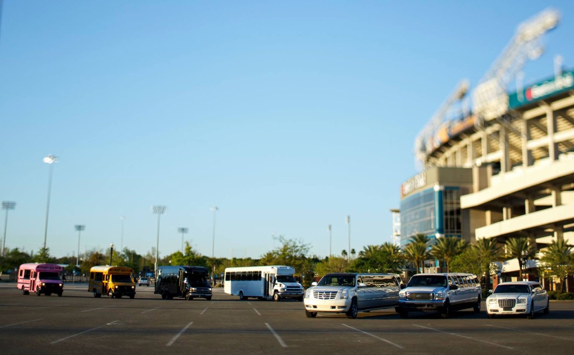 Parking lot outside a stadium with several cars under a blue sky
