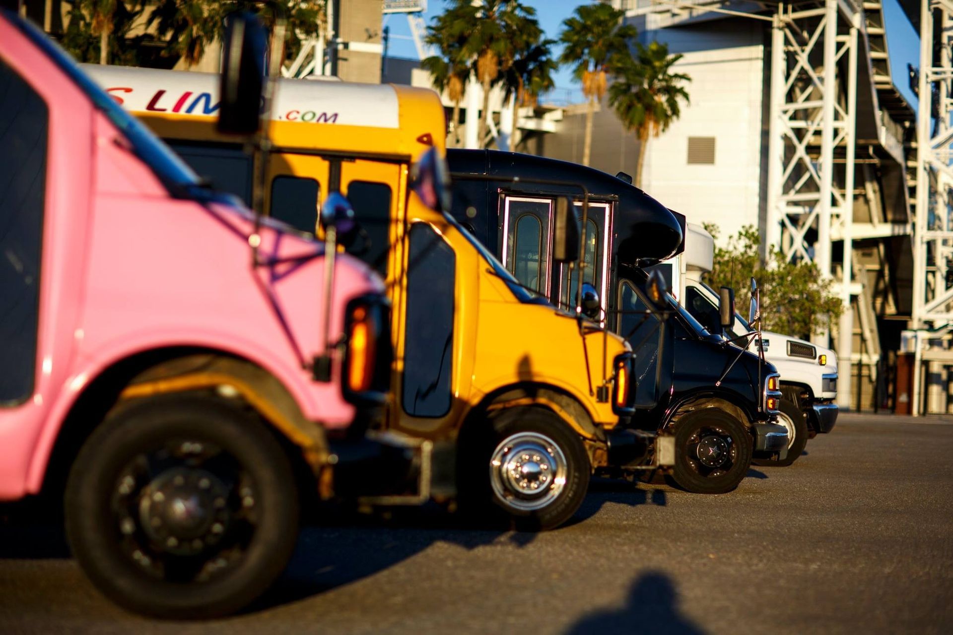 Colorful delivery trucks parked in a row outdoors, with a pink truck in the foreground.