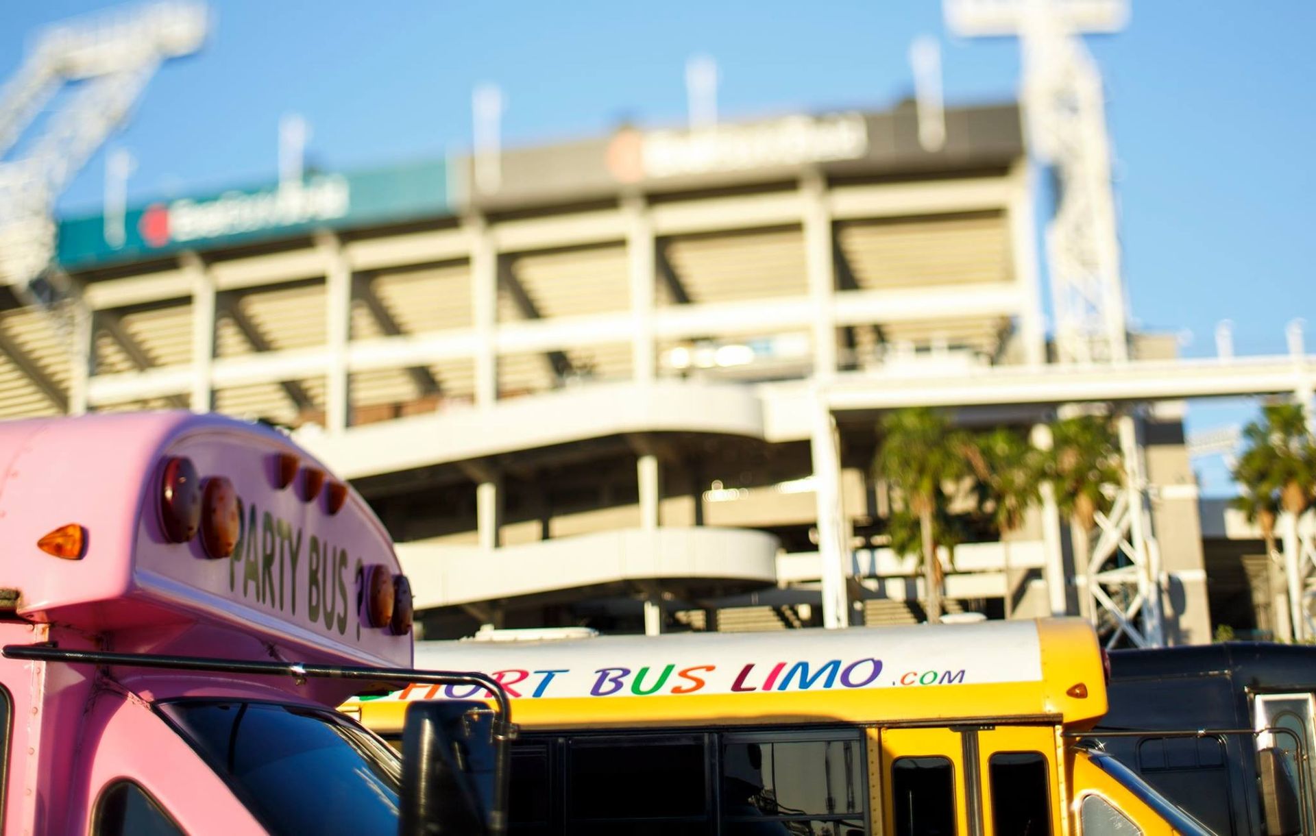 Pink and yellow airport shuttle buses parked in front of a multi-level terminal building