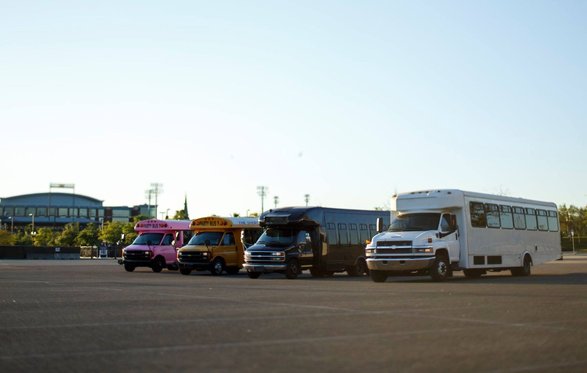 Four colorful food trucks parked on a wide paved lot under a clear sky.