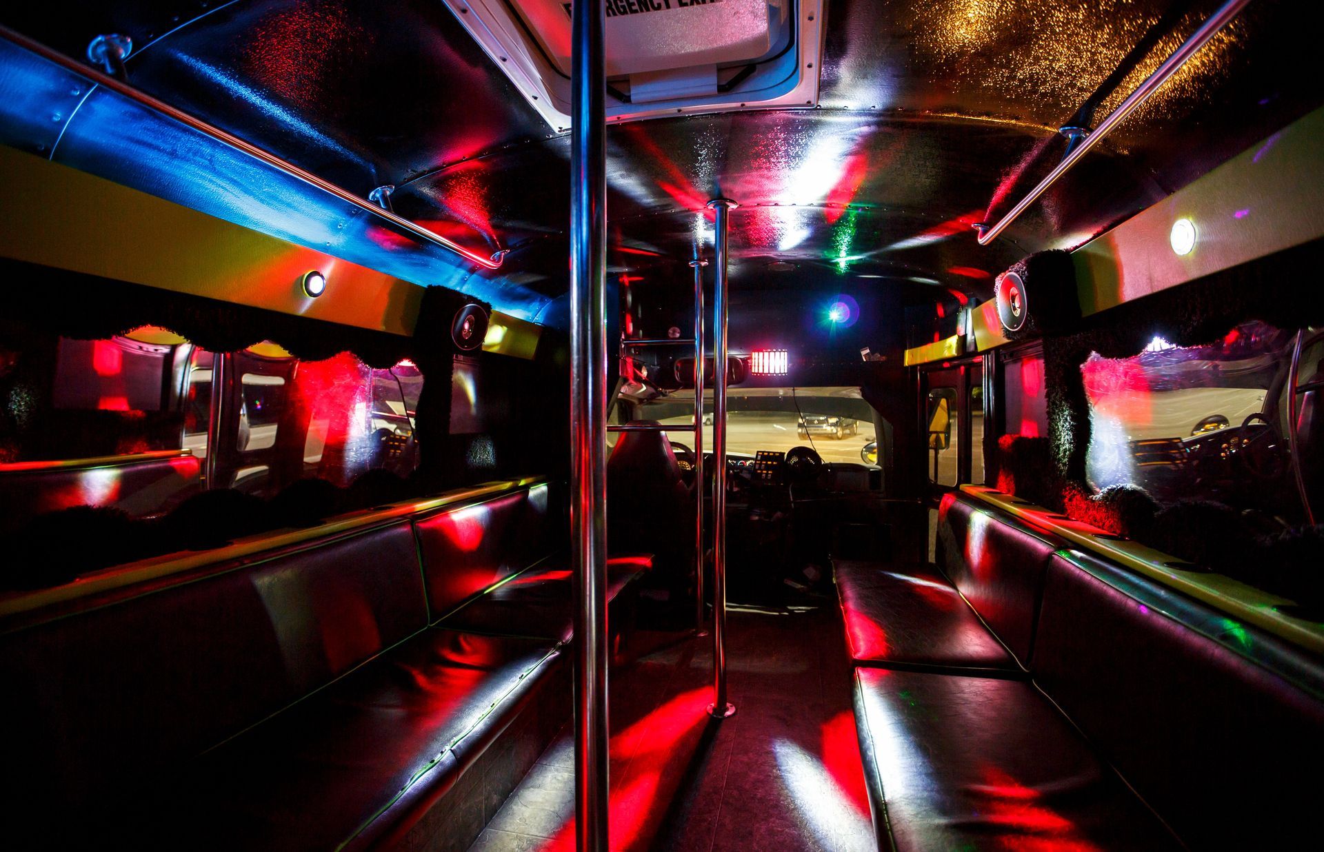 Neon-lit empty bus interior with red, blue, and pink reflections on chrome rails