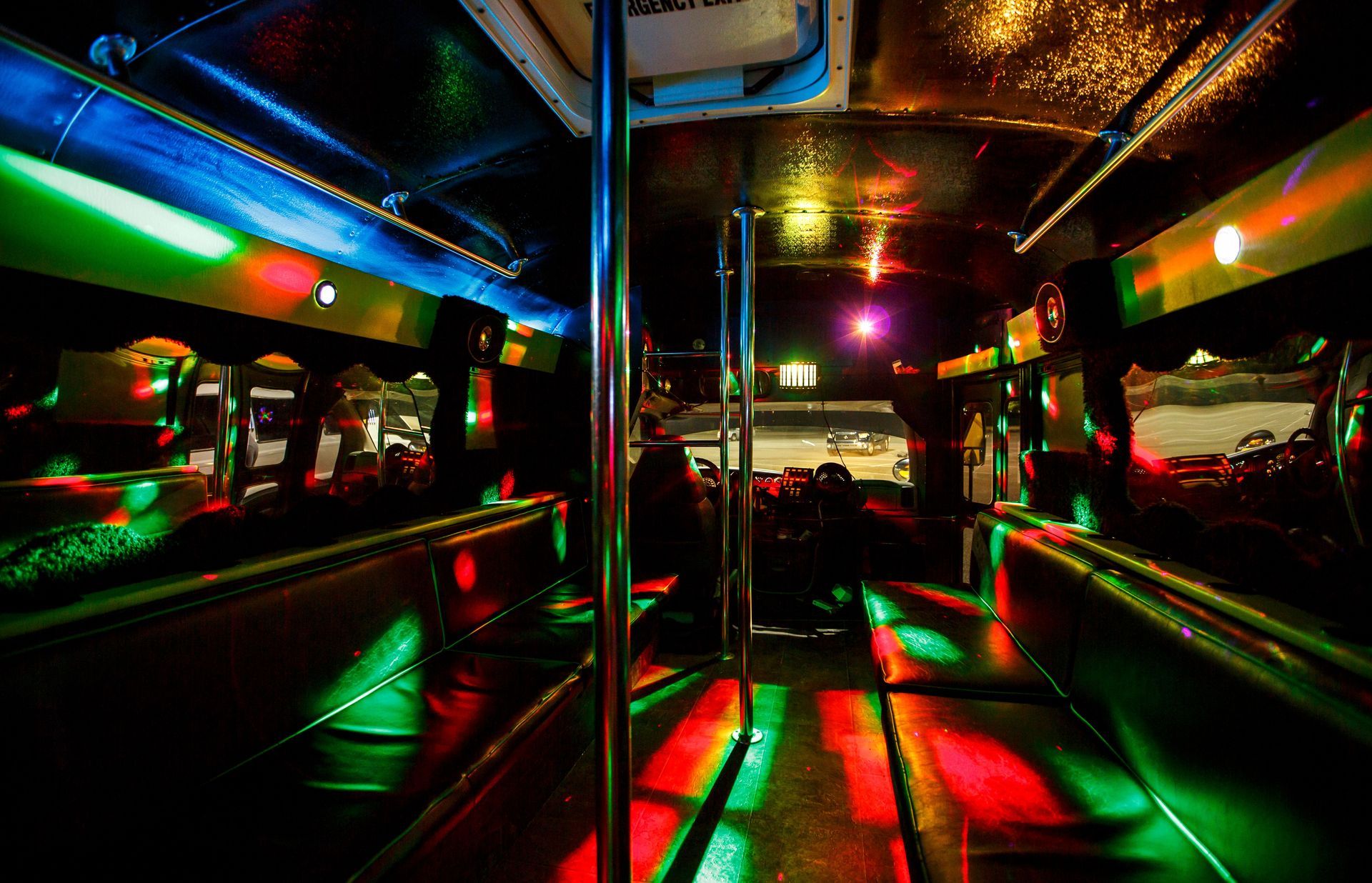Neon-lit bus interior with colorful reflections and empty seats at night