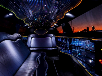 Luxury limo interior with blue LED lights, black leather seats, and a city sunset view through the windows