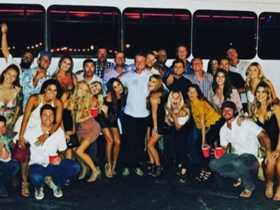 Large group posing together at night in front of a bus, smiling and dressed in casual clothes.