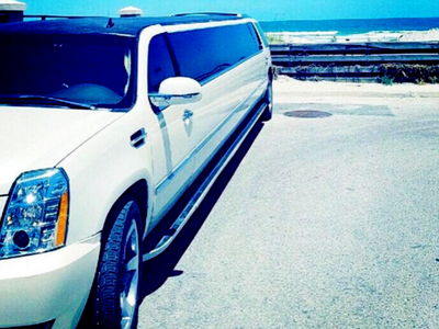 White stretch limousine parked on a sunny beach beside the ocean