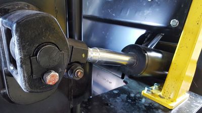 A close up of a metal object with a yellow pole in the background.