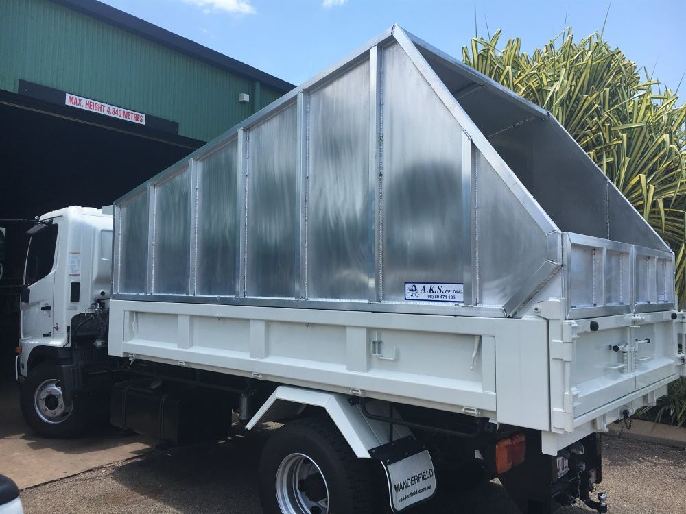 A White Dump Truck is Parked in Front of a Building — AKS Welding & Fabrication in Winnellie, NT