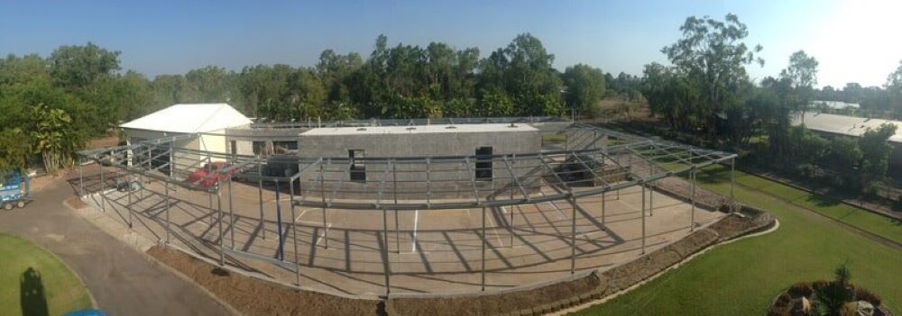 An aerial view of a building under construction with a lot of trees in the background.