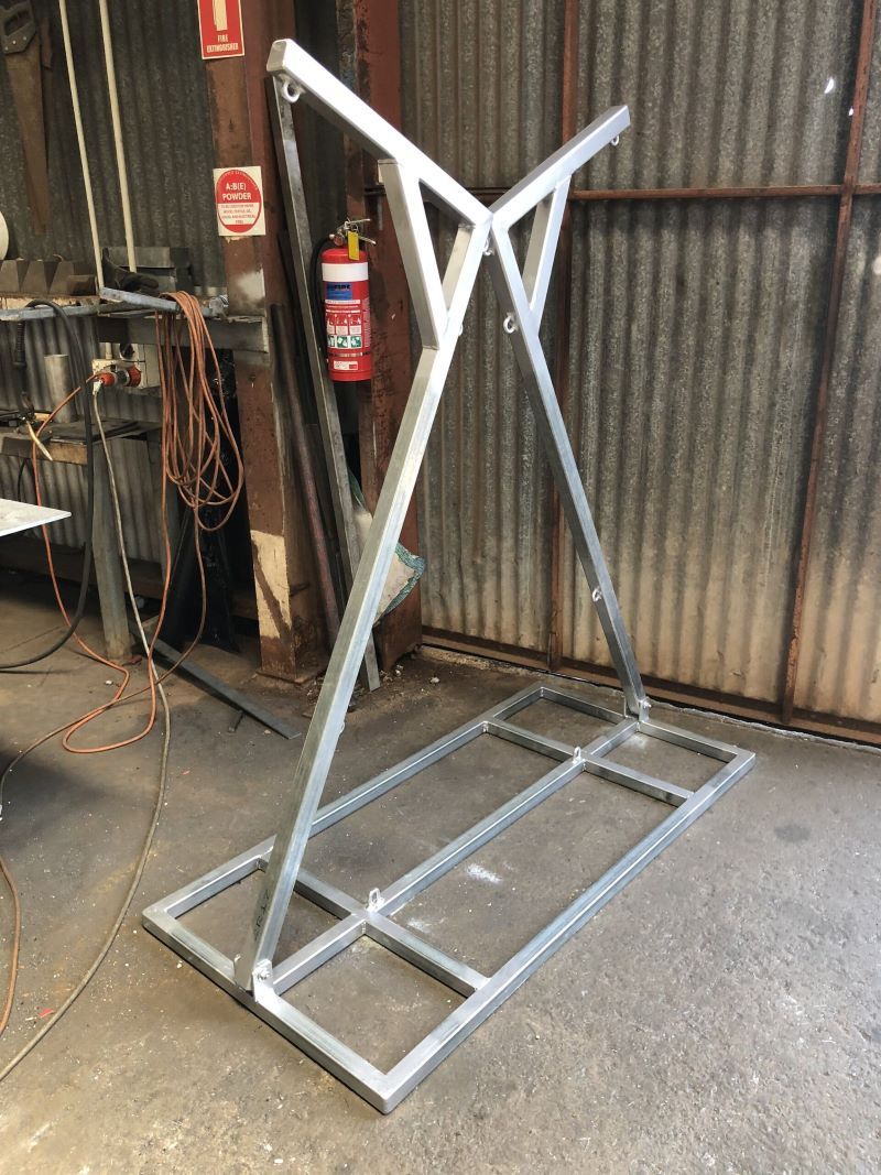 A Metal Frame is Sitting in a Warehouse Next to a Fire Extinguisher — AKS Welding & Fabrication in Winnellie, NT