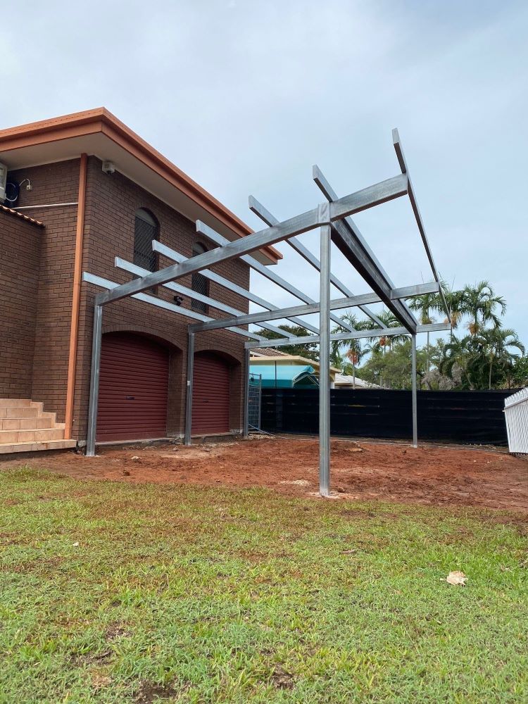 A Metal Pergola is Being Built in Front of a Brick House — AKS Welding & Fabrication in Winnellie, NT