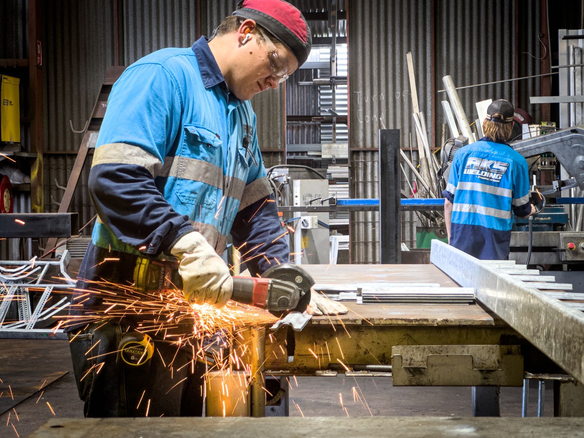 A man wearing a hard hat and safety vest is welding a metal structure. — AKS Welding & Fabrication in Winnellie, NT