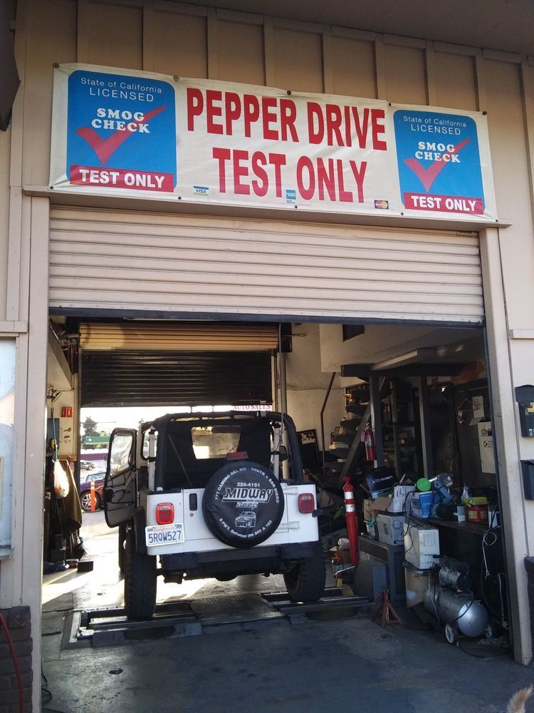 White Jeep in a red-and-blue “Pepper Drive Test Only” auto service bay