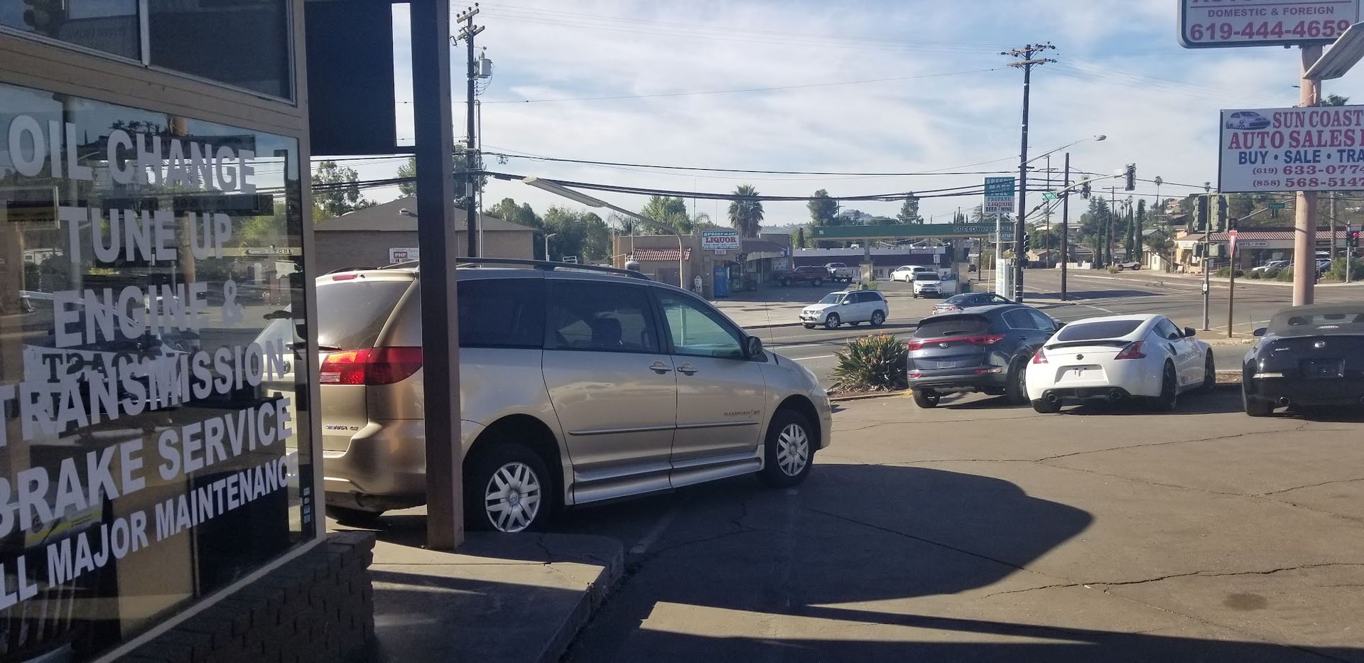 Parking lot with several cars and an auto repair shop sign listing services on the left.